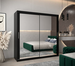 Modern bedroom with a large black wardrobe with sliding doors, green bed, and decorative elements.