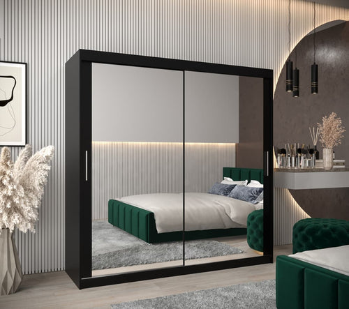 Modern bedroom with a large black wardrobe with sliding doors, green bed, and decorative elements.