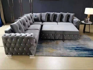 Gray sectional sofa in a living room setting with a rug and lamp.