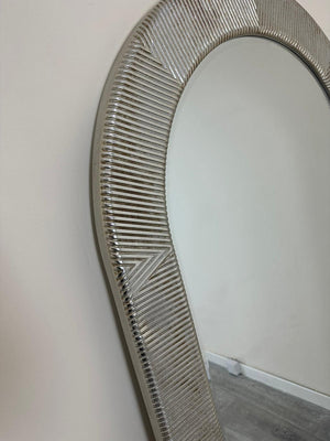Round mirror with a decorative silver frame on a plain wall.