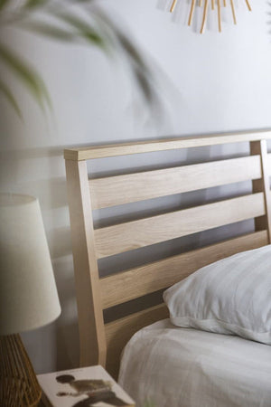 Wooden headboard with a lamp and pillow in a bedroom setting