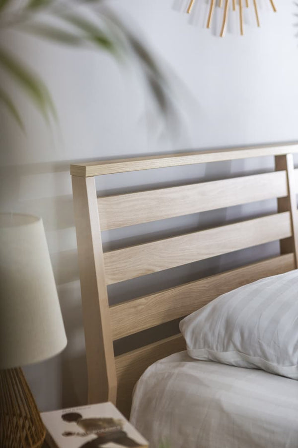 Wooden headboard with a lamp and pillow in a bedroom setting