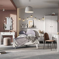 Modern bedroom with pink walls, gray headboard, and white furniture.