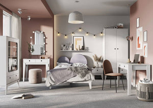 Modern bedroom with pink walls, gray headboard, and white furniture.