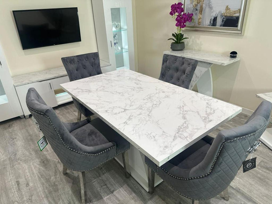Dining room with marble table and gray chairs, TV mounted on wall.