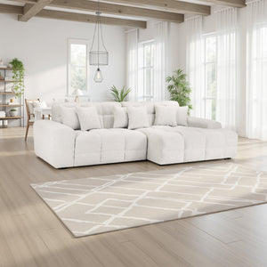 White sectional sofa in a modern living room with large windows and a patterned rug.