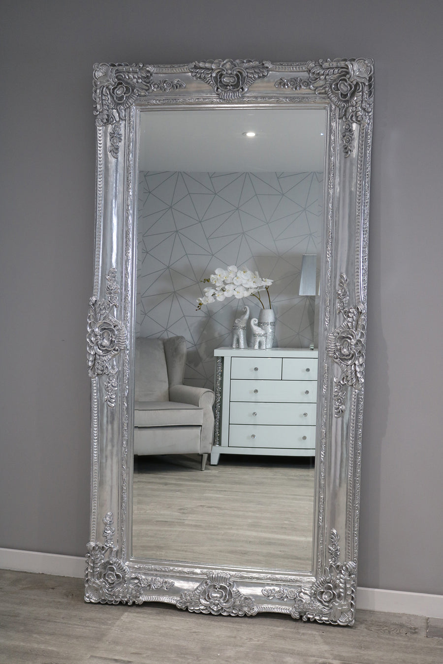 Decorative muted brownish-grey mirror with intricate frame on a Grey wall