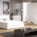 Modern bedroom with white furniture, including a bed and dresser, on a wooden floor.
