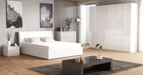 Modern bedroom with white furniture, including a bed and dresser, on a wooden floor.