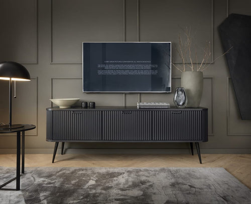 Modern living room with a television mounted on a gray wall, a sideboard with decorative items, and a lamp.