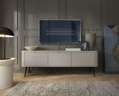 Modern living room with a television on a white console table, decorative items, and a dark wall.