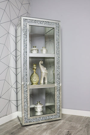 Decorative glass cabinet with embellished frame against a gray wall with geometric pattern.