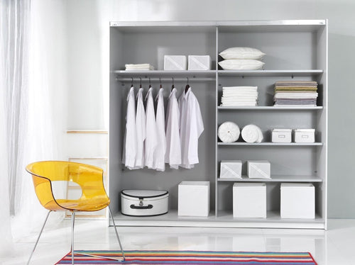 Closet with white shelves, clothes, and storage boxes with a yellow chair in the foreground.
