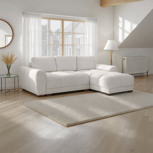 White sectional sofa in a bright living room with large windows.