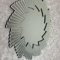 Decorative wall mirror with a sunburst design on a textured wall.
