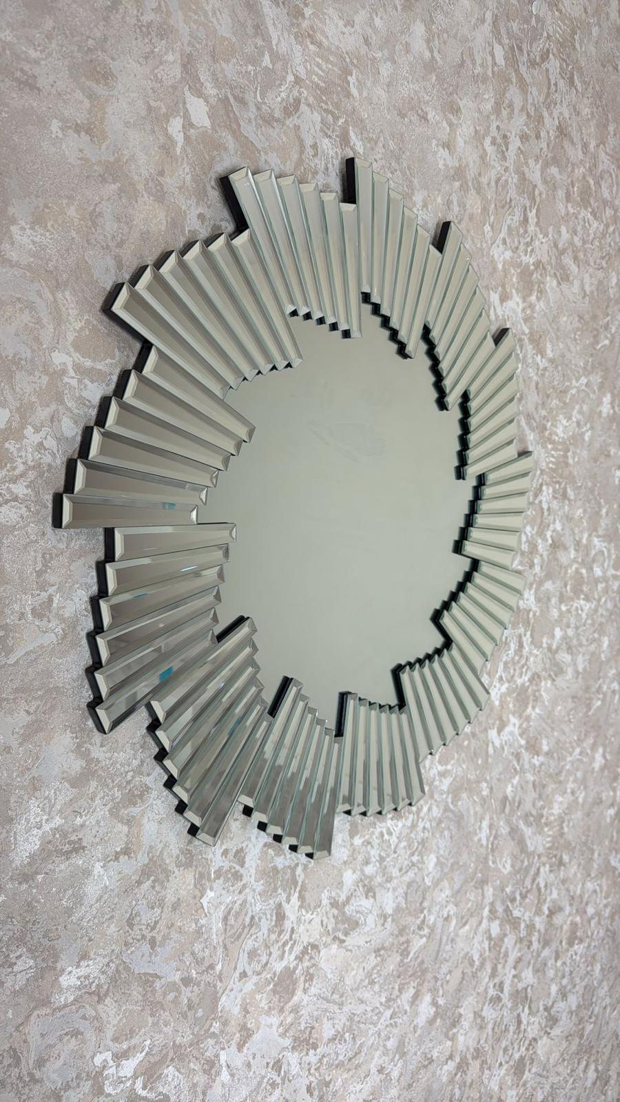 Decorative wall mirror with a sunburst design on a textured wall.