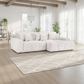 White sectional sofa in a modern living room with large windows and a patterned rug.