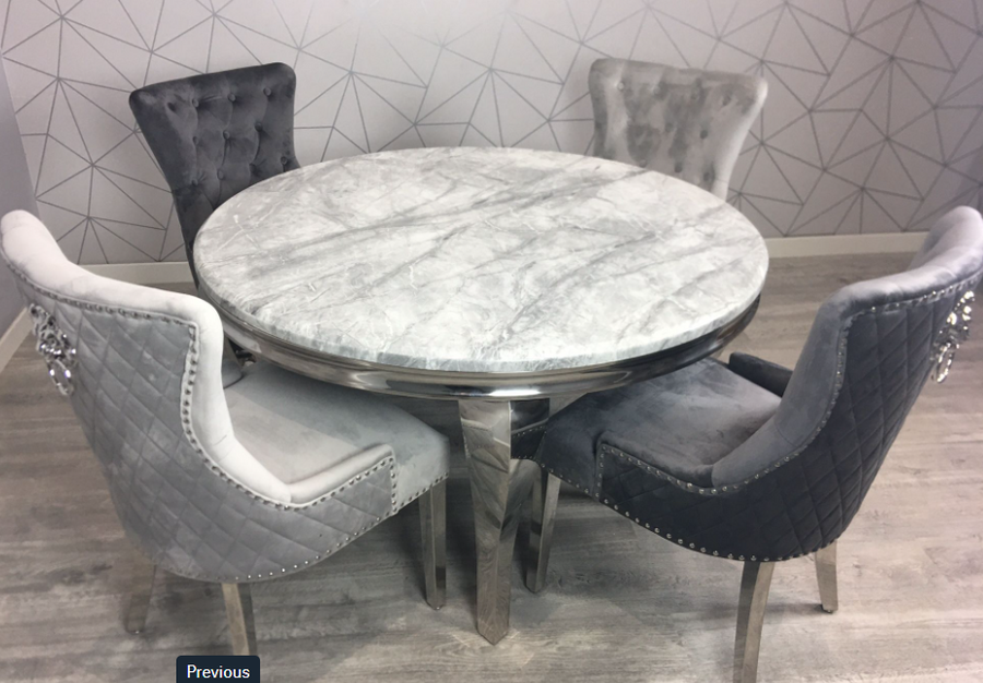 Round marble table with four gray upholstered chairs against a geometric patterned wall.