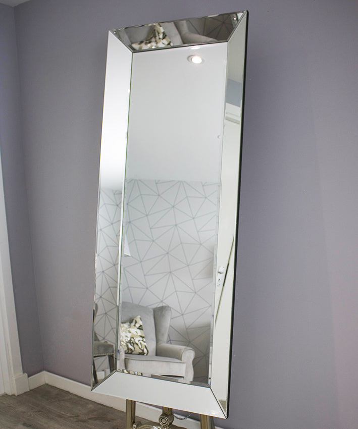Tall rectangular mirror leaning against a gray wall with a geometric patterned wallpaper.