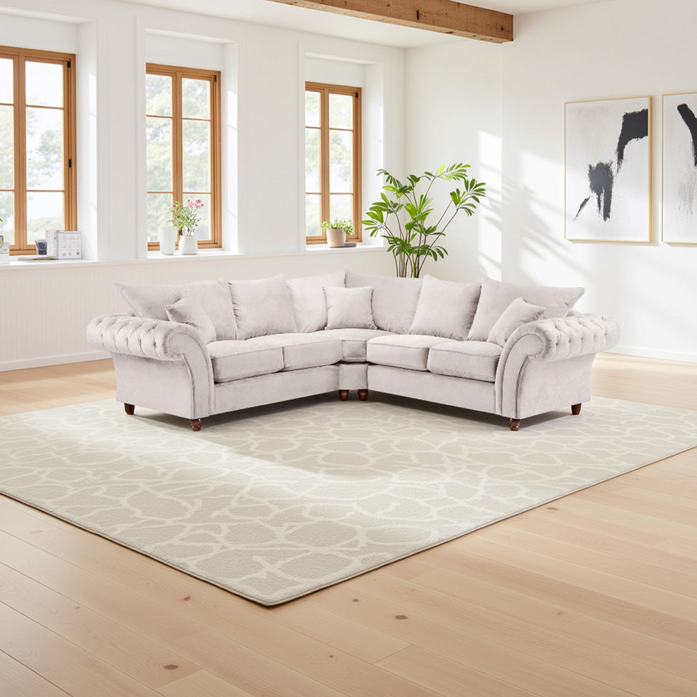 Light gray sectional sofa in a bright living room with large windows and a rug.