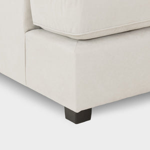 Close-up of a beige sofa with a black leg on a light gray background